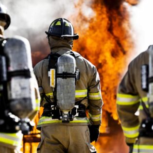 a group of firefighters in full gear walking toward flames