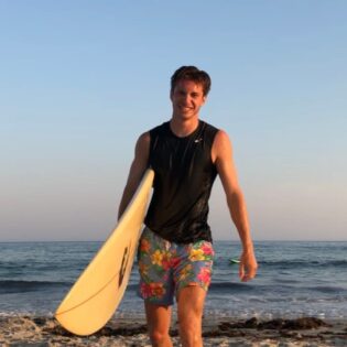 Jack Gunning walking on the beach with surf board under his arm