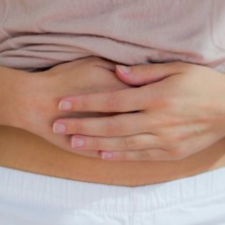 young woman's folded hands over lower belly