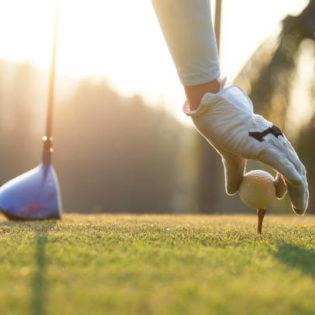 A golfer placing a golf ball on a tee